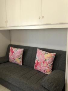 a gray couch with two pink pillows on it at Appartamento vicino al mare e al centro in Alghero