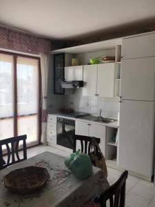 a kitchen with a table and a white refrigerator at Appartamento vicino al mare e al centro in Alghero