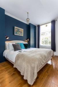 ロンドンにあるDear Newton One Bedroom in Notting Hillの青い壁のベッドルーム1室(大型ベッド1台付)