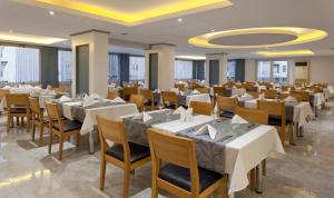 un comedor con mesas y sillas blancas en Monart City Hotel - All Inclusive Plus en Alanya
