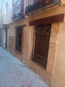 a brick building with barred windows on a street at SEÑORÍO de ORGAZ "Con Patio TOLEDANO" in Toledo