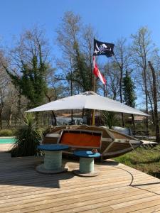 a boat sitting under an umbrella on a deck at Au Bois Flotté in Hourtin