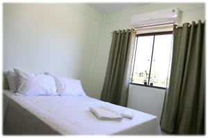 a bedroom with a bed with white sheets and a window at Bonito Residencial Flat in Bonito