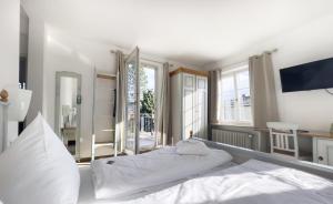 a large white bed in a room with white walls at Hotel Auf d´ Steig in Lindau
