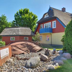 a house with a red building and a pile of rocks at "Kombüse" by Ferienhaus Strandgut in Born