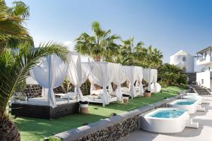 a row of chairs and a pool at a resort at Smy Mediterranean White Santorini in Kamari