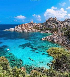 een uitzicht op een strand met blauw water en rotsen bij Capotesta Luxury Rooms in Santa Teresa Gallura