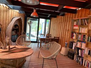 a room with chairs and tables and bookshelves at Au Bois Flotté in Hourtin