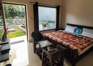 ein Schlafzimmer mit einem Bett, einem Fenster und einem Stuhl in der Unterkunft Anugraha Homestay in Rāmnagar