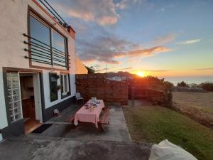 a patio with a table and the sunset in the background at Casa da Lomba do Cavaleiro in Povoação