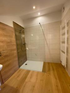a bathroom with a shower and a wooden floor at Feriendorf Büchelberg in Windorf