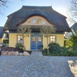 una casa amarilla con puerta azul en "Schiffszimmermannshaus" by Ferienhaus Strandgut, en Born
