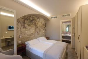 a bedroom with a white bed and a stone wall at Relais Villa Porta in Luino