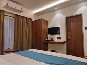 a hotel room with a bed and a tv at Hotel El Magnifico in Surat
