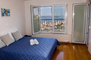 a bedroom with a blue bed and large windows at Apartments Villa San Antonio in Crikvenica