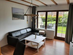 a living room with a black leather couch and a table at Beiboot in Wangerland +1 photo