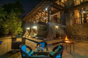 an outdoor patio with chairs and a fire place at SaffronStays Vedika - 4BR riverfront pool villa with kaya king bullock ride & BBQ near Pinjal River, Vikramgad in Pālghar
