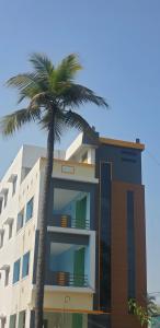 a tall building with a palm tree in front of it at SSK HOME STAY in Puducherry
