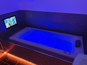 een blauw bad met een tv in de badkamer bij Luxurious 4 bedroom home in the heart of the Cotswolds with Hot Tub! in Stow on the Wold