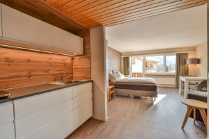 eine Küche und ein Wohnzimmer mit einem Bett im Hintergrund in der Unterkunft Rhodania 56 in Riederalp