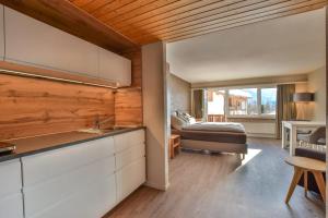 eine Küche und ein Wohnzimmer mit einem Bett im Hintergrund in der Unterkunft Rhodania 56 in Riederalp