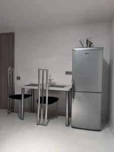 a kitchen with a table and a refrigerator at Butas Prie Nemuno in Druskininkai