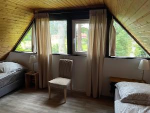 a bedroom with two beds and a chair and two windows at Ferienwohnung Hemmerle in Bispingen