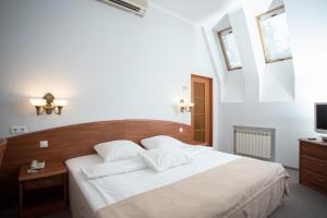 1 dormitorio con 1 cama blanca grande y TV en Hotel Amparo, en Cherepovets
