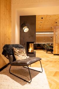 a living room with a chair and a fireplace at Ferienhotel Jörglerhof in Hainzenberg