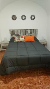 Un dormitorio con una gran cama gris con almohadas naranjas en Casa Rural cueva cerros en Fuentidueña de Tajo