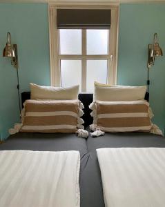 カンペルラントにあるHet Koetshuisのベッド2台、枕、窓が備わる客室です。