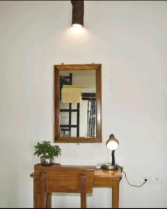 a mirror on a wall next to a table with a lamp at MONALISA HOSTEL in Varanasi