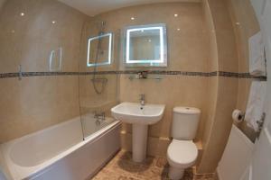 a bathroom with a toilet and a sink and a bath tub at The Helaina Apartments in Scarborough +38 photos