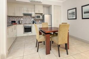 a kitchen with a wooden table and chairs at Harbour House Hotel - Harbour Square in Hermanus