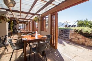 a patio with a wooden table and chairs on it at Harbour House Hotel - Harbour Square in Hermanus