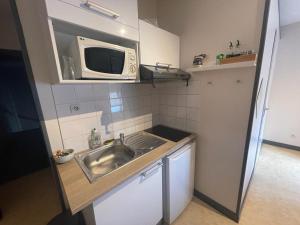 a small kitchen with a sink and a microwave at Studio agréable et lumineux in Niort