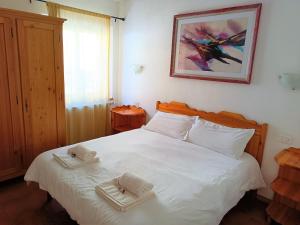 Un dormitorio con una cama blanca con toallas. en Cottage Abetone La Capanna in Tuscany, en Abetone