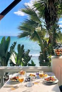 una mesa con dos platos de comida y copas de vino en New 2023 Don Gustavo, Beach Front, Sea Views, en Benalmádena