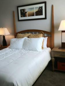 um quarto com uma cama com lençóis brancos e almofadas em Villa Verde Surprise Stadium - Resort Living em Surprise