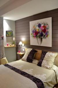 um quarto com uma cama com uma pintura de flores na parede em les tamaris em Castelnau-sur-Gupie