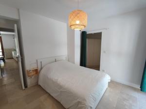 una camera da letto con un letto bianco e un lampadario di Le THIERS-TEMPS - AC CLIM - GRANDE TERRASSE - PROCHE THEATRES ad Avignone