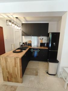 una cucina con bancone in legno e frigorifero nero di Le THIERS-TEMPS - AC CLIM - GRANDE TERRASSE - PROCHE THEATRES ad Avignone