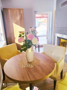 un jarrón de flores sentado en una mesa de madera en Apartamenty Golden Village en Duszniki Zdrój