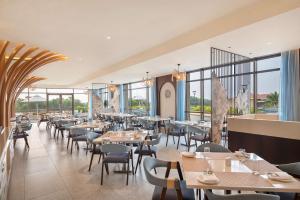 a restaurant with tables and chairs and windows at Radisson Blu Resort Visakhapatnam in Visakhapatnam