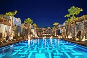 a hotel pool with chairs and palm trees at night at Radisson Blu Zaffron Resort, Santorini in Kamari