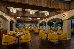a dining room with tables and yellow chairs at Mar Monte Hotel, in The Unbound Collection by Hyatt in Santa Barbara