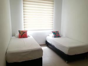 two beds sitting in a room with a window at HERMOSO APARTAMENTO EN GIRARDOT CON AIRE ACONDICIONADO in Girardot