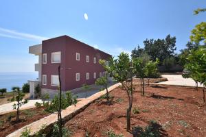 a red building with trees in front of it at Dima Vista in Dhërmi