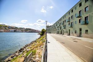 una strada vuota accanto a un edificio vicino a un corpo d'acqua di Douro Destilaria Residence by Porto City Hosts a Vila Nova de Gaia