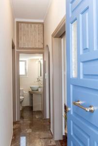 a bathroom with a toilet and a blue door at Θἔρως (Theros) house 1 - Agios Fokas in Tinos